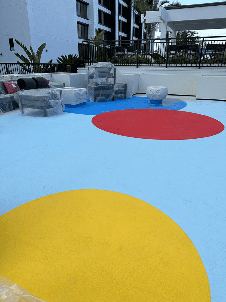 Pixar Place Finished MACoat Blue, red, and yellow circles decorate the pool deck main area